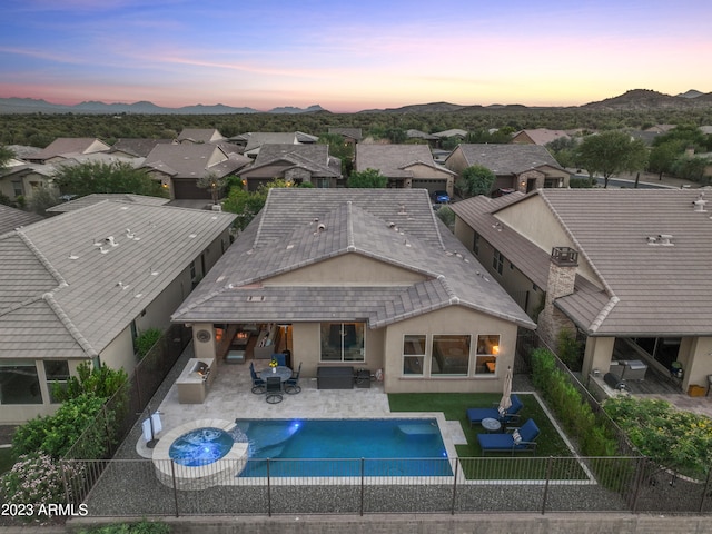 pool at dusk featuring an outdoor hangout area, a mountain view, and a patio