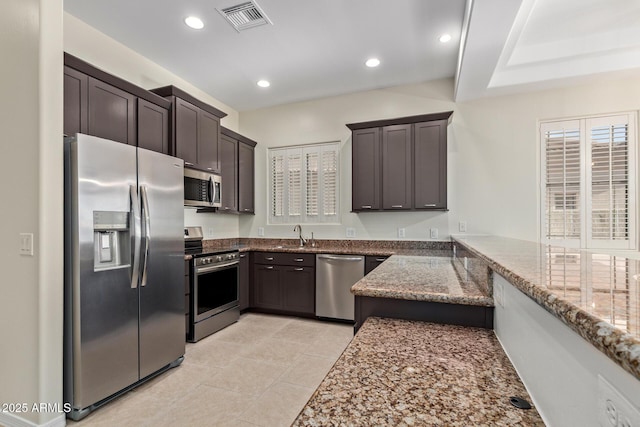 6202 E Mckellips Rd Unit 25, Mesa, AZ 85215 - kitchen featuring appliances with stainless steel finishes, dark stone countertops, dark brown cabinetry, light tile patterned floors, and recessed lighting