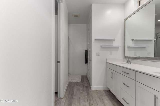 full bath with visible vents, vanity, baseboards, and wood finished floors