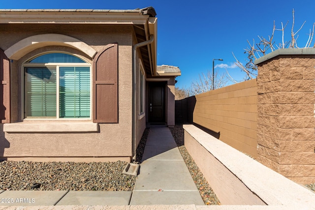 entrance to property with fence and stucco siding