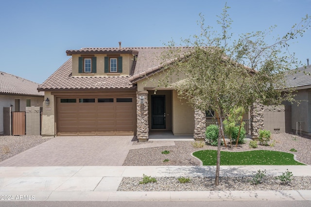 view of front of property featuring stucco siding, fence, an attached garage, a tiled roof, and decorative driveway