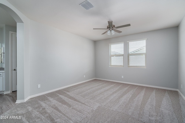 spare room featuring baseboards, visible vents, arched walkways, and a ceiling fan