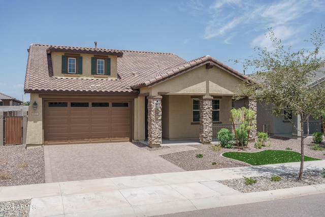 mediterranean / spanish home with a tiled roof, a porch, decorative driveway, and stucco siding