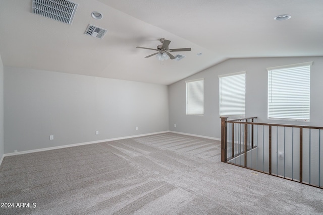 carpeted spare room featuring ceiling fan, baseboards, vaulted ceiling, and visible vents