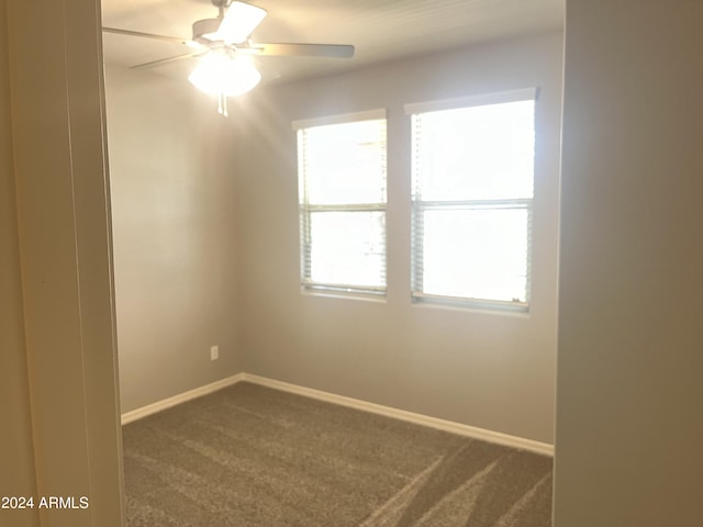 spare room featuring dark carpet and ceiling fan