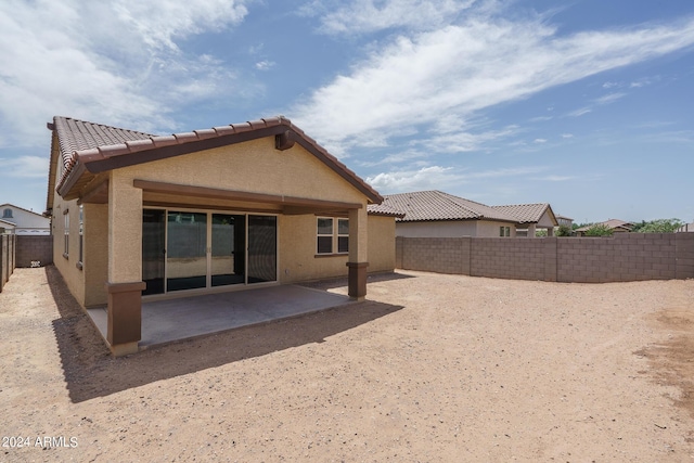 rear view of house featuring a fenced backyard, a tiled roof, stucco siding, and a patio area