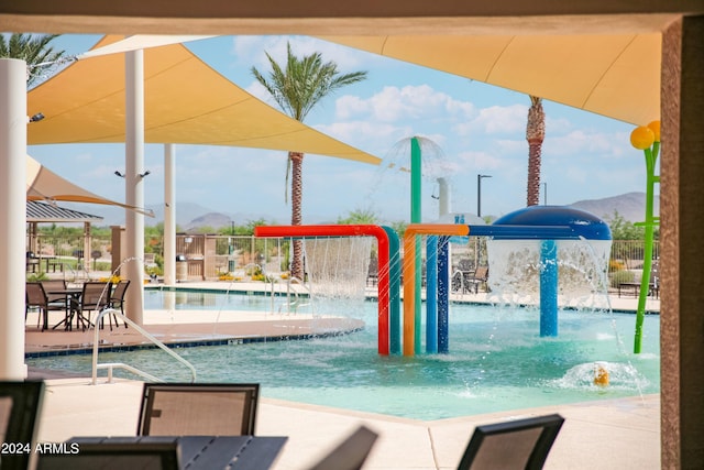 view of swimming pool featuring playground community, fence, and a mountain view