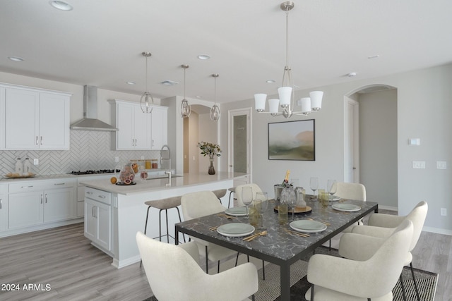 dining room featuring visible vents, light wood finished floors, baseboards, recessed lighting, and arched walkways
