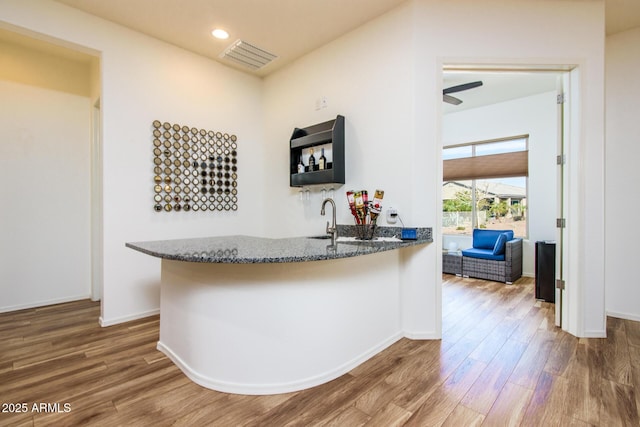 bar featuring baseboards, visible vents, indoor wet bar, and wood finished floors