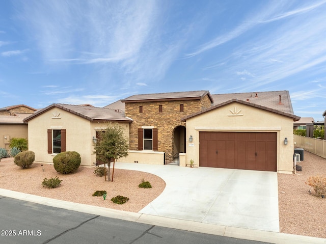 view of front of house featuring a garage, fence, stone siding, concrete driveway, and stucco siding