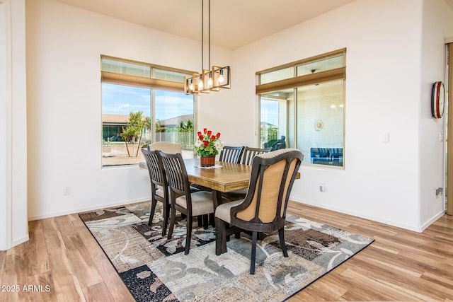 dining space featuring light wood-style flooring, baseboards, and a notable chandelier