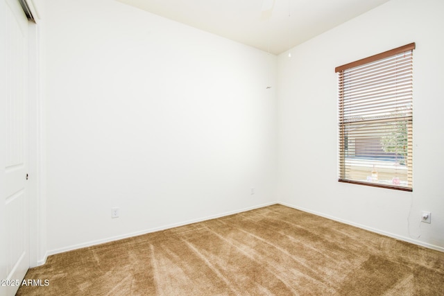 carpeted spare room featuring baseboards