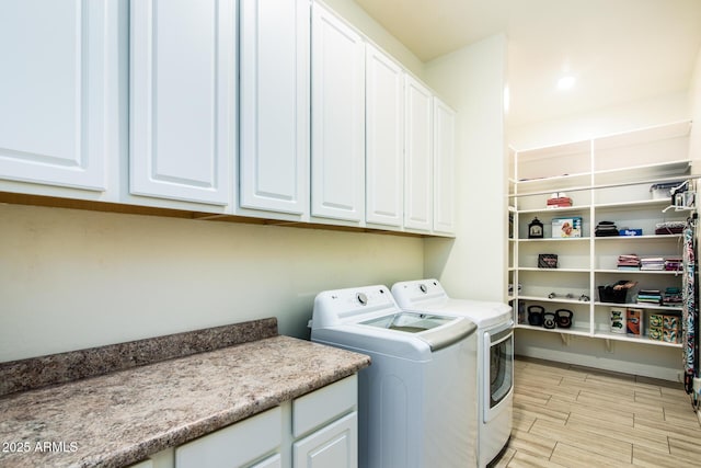 laundry area featuring cabinet space, wood finish floors, and washing machine and clothes dryer