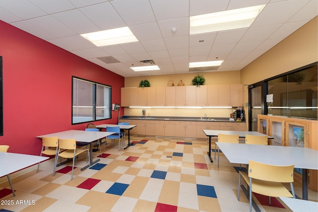 kitchen featuring a paneled ceiling, visible vents, a sink, and cream cabinets