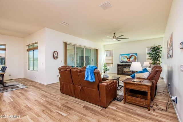 living room with a ceiling fan, light wood-type flooring, and visible vents