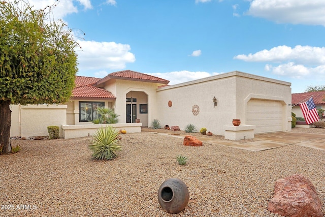 mediterranean / spanish home featuring driveway, an attached garage, a tiled roof, and stucco siding