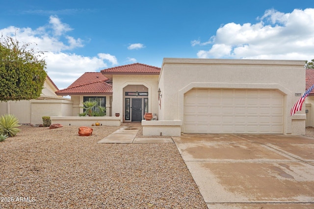 mediterranean / spanish home with a garage, driveway, a tiled roof, and stucco siding