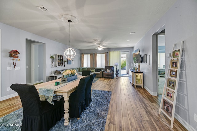 dining room featuring ceiling fan with notable chandelier and hardwood / wood-style flooring