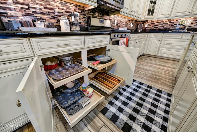 kitchen with decorative backsplash, light hardwood / wood-style floors, white cabinetry, and stainless steel appliances