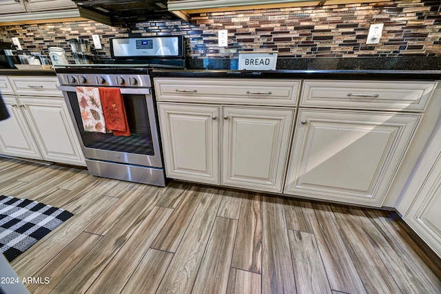 kitchen with stainless steel range, tasteful backsplash, light hardwood / wood-style flooring, and white cabinetry