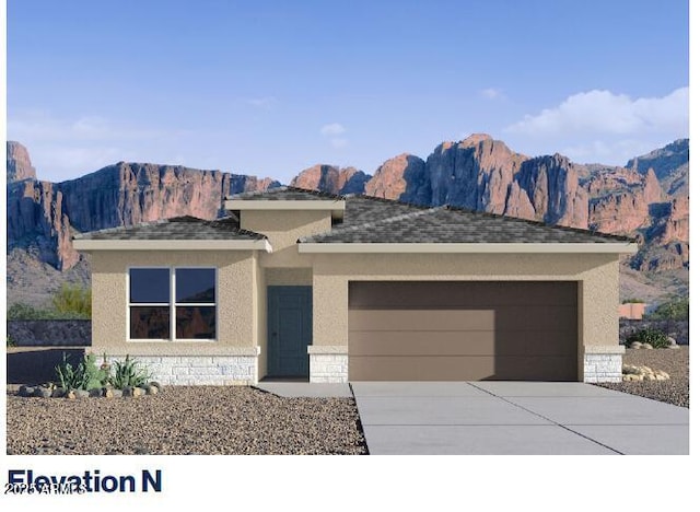 prairie-style home featuring a garage, a mountain view, concrete driveway, and stone siding