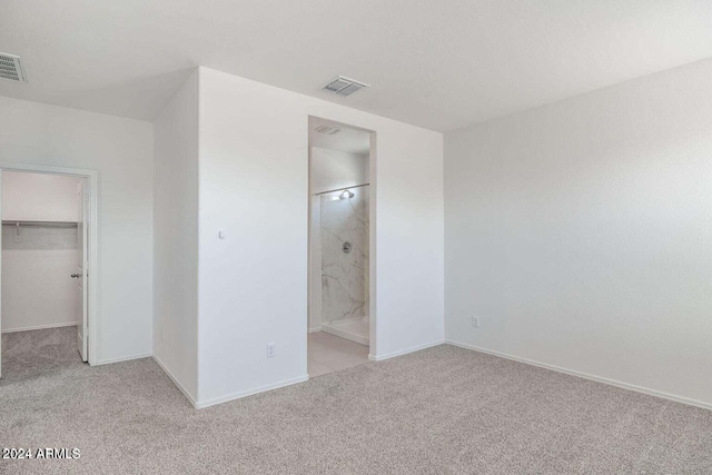 unfurnished bedroom with a walk in closet, carpet floors, baseboards, visible vents, and a closet