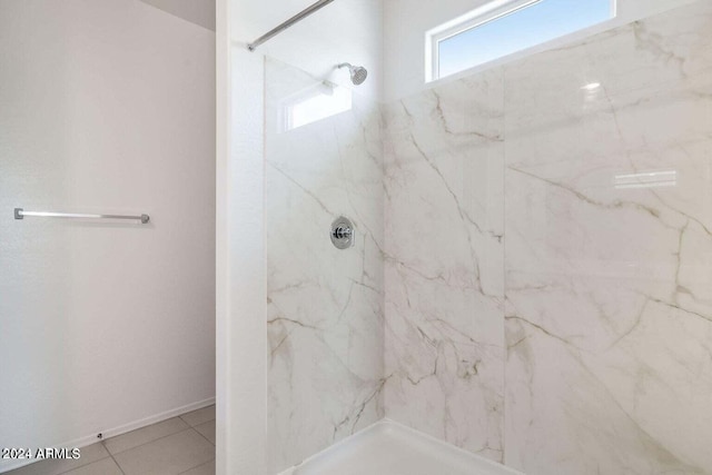 bathroom with a marble finish shower and tile patterned floors