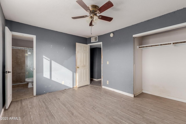 unfurnished bedroom featuring ceiling fan, ensuite bath, light hardwood / wood-style floors, and a closet