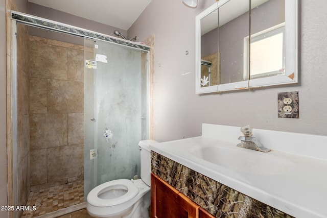 bathroom featuring vanity, a shower with shower door, and toilet