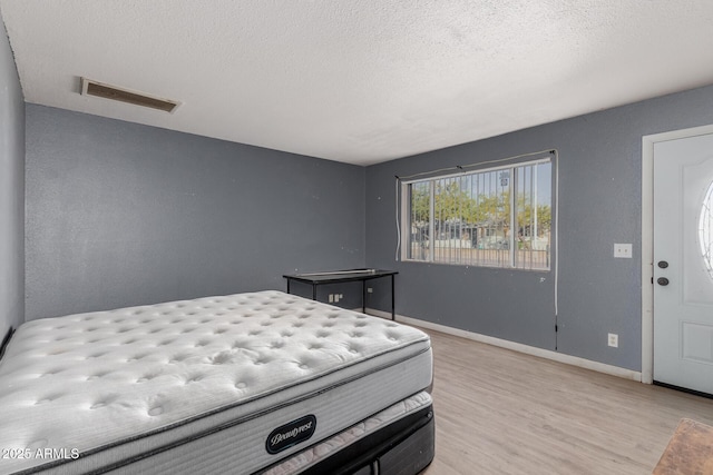 bedroom with a textured ceiling and light hardwood / wood-style floors