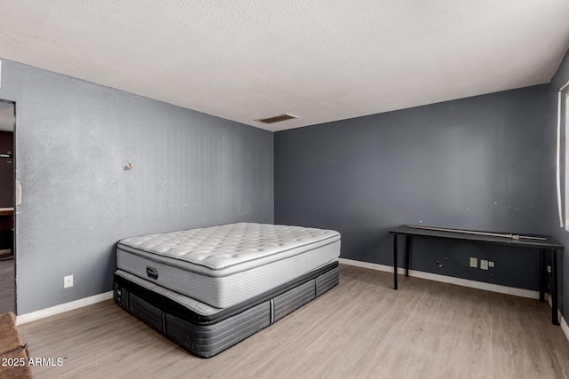 bedroom with light hardwood / wood-style flooring and a textured ceiling