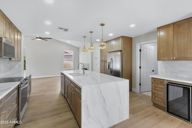 kitchen with backsplash, sink, wine cooler, an island with sink, and stainless steel appliances