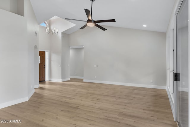 unfurnished living room featuring light hardwood / wood-style flooring, high vaulted ceiling, and ceiling fan with notable chandelier