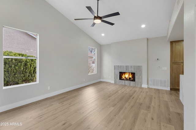 unfurnished living room featuring ceiling fan, light hardwood / wood-style floors, a fireplace, and high vaulted ceiling