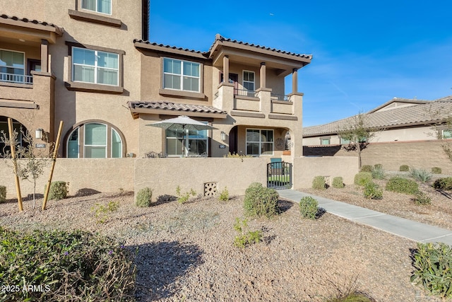 view of front of house featuring fence private yard, a gate, a tiled roof, and stucco siding