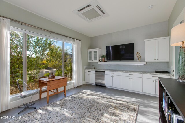 kitchen featuring white cabinets, decorative backsplash, and a healthy amount of sunlight