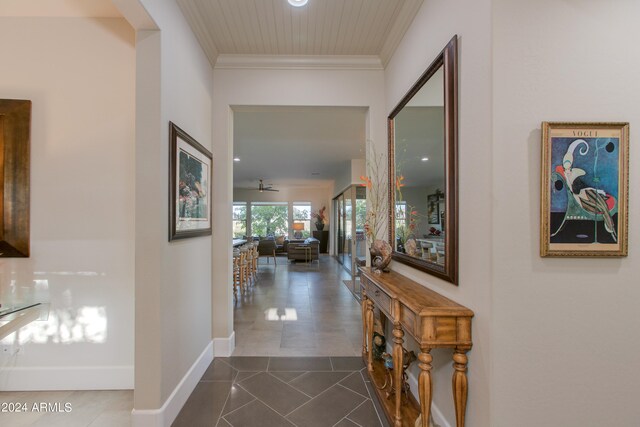 corridor featuring ornamental molding and dark tile patterned floors