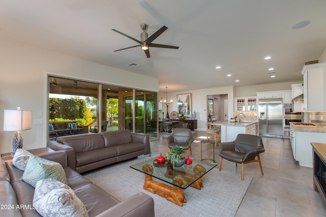 tiled living room with ceiling fan with notable chandelier and sink