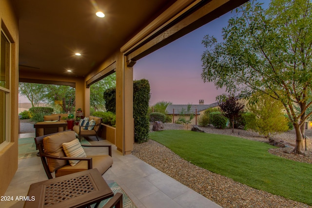 patio terrace at dusk featuring outdoor lounge area and a yard