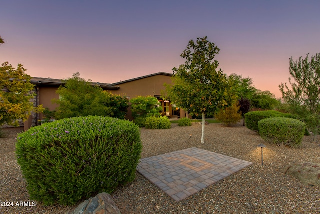 yard at dusk featuring a patio