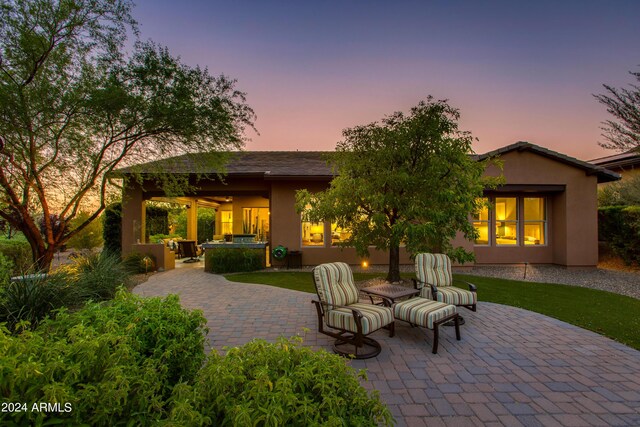 back house at dusk with area for grilling, ceiling fan, and a patio area