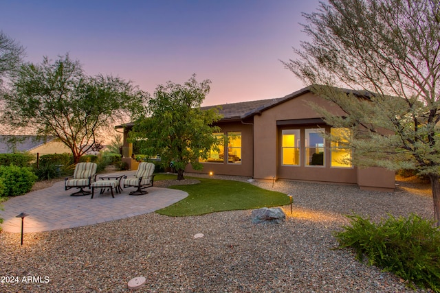 back house at dusk with a patio area