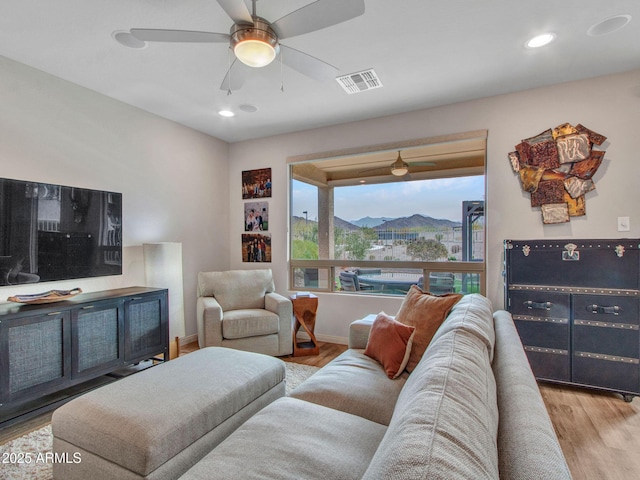 living room featuring ceiling fan, a mountain view, and light hardwood / wood-style flooring