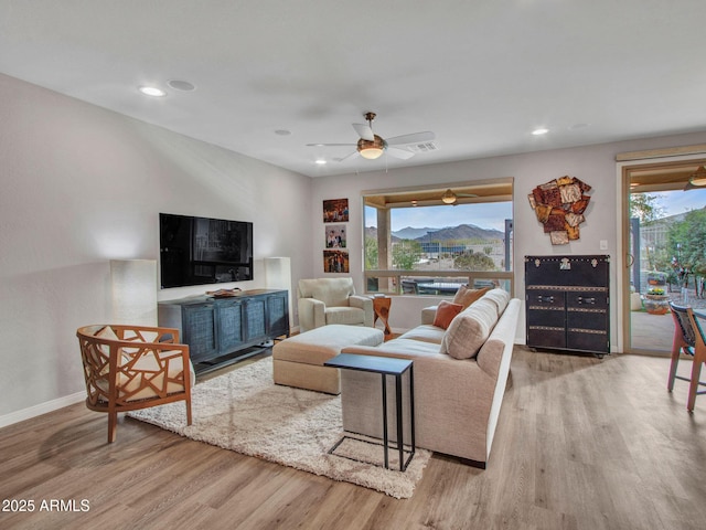 living room with ceiling fan, light hardwood / wood-style floors, and a wealth of natural light