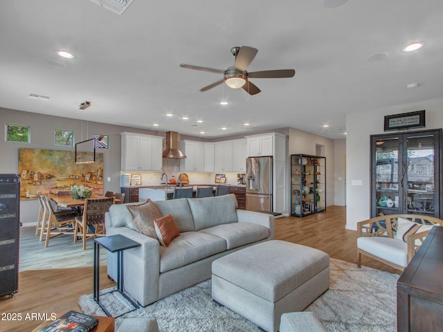 living room featuring ceiling fan, sink, and light hardwood / wood-style flooring