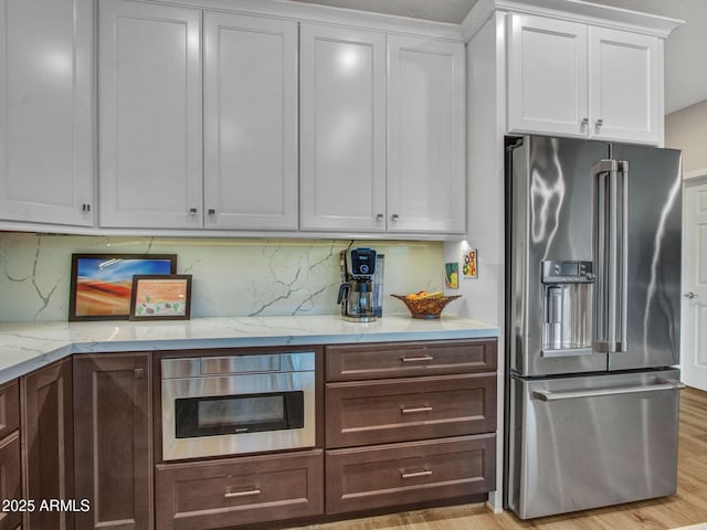 kitchen featuring white cabinetry, appliances with stainless steel finishes, light hardwood / wood-style flooring, and backsplash