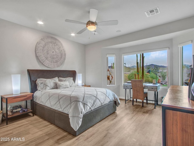 bedroom featuring multiple windows, a mountain view, ceiling fan, and light hardwood / wood-style floors