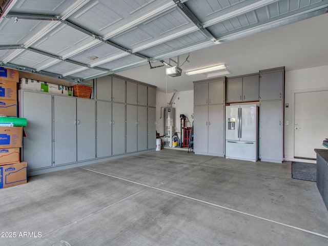 garage with a garage door opener, gas water heater, and refrigerator with ice dispenser