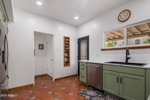kitchen with stainless steel appliances, green cabinets, light countertops, and a sink