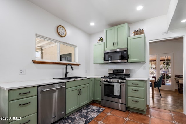 kitchen featuring green cabinetry, appliances with stainless steel finishes, light countertops, and a sink